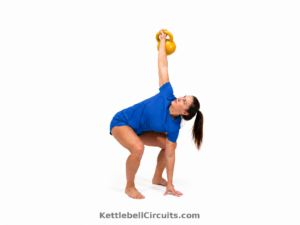 Athlete performing a kettlebell rotational press with the foot pivoting and hips rotating as the bell presses overhead.